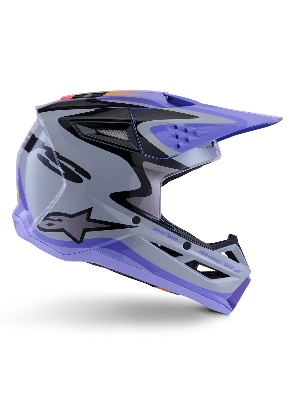 Alpinestars S-M3 Jettson Youth Helmet, capacete de motocross, cinzento, roxo e preto brilhante, perfil lateral com grafismos angulares nítidos e marca 'Jettson Donuts', design de calota aerodinâmica com aberturas de ventilação e logótipo Alpinestars, equipamento de proteção off-road de alto desempenho para jovens