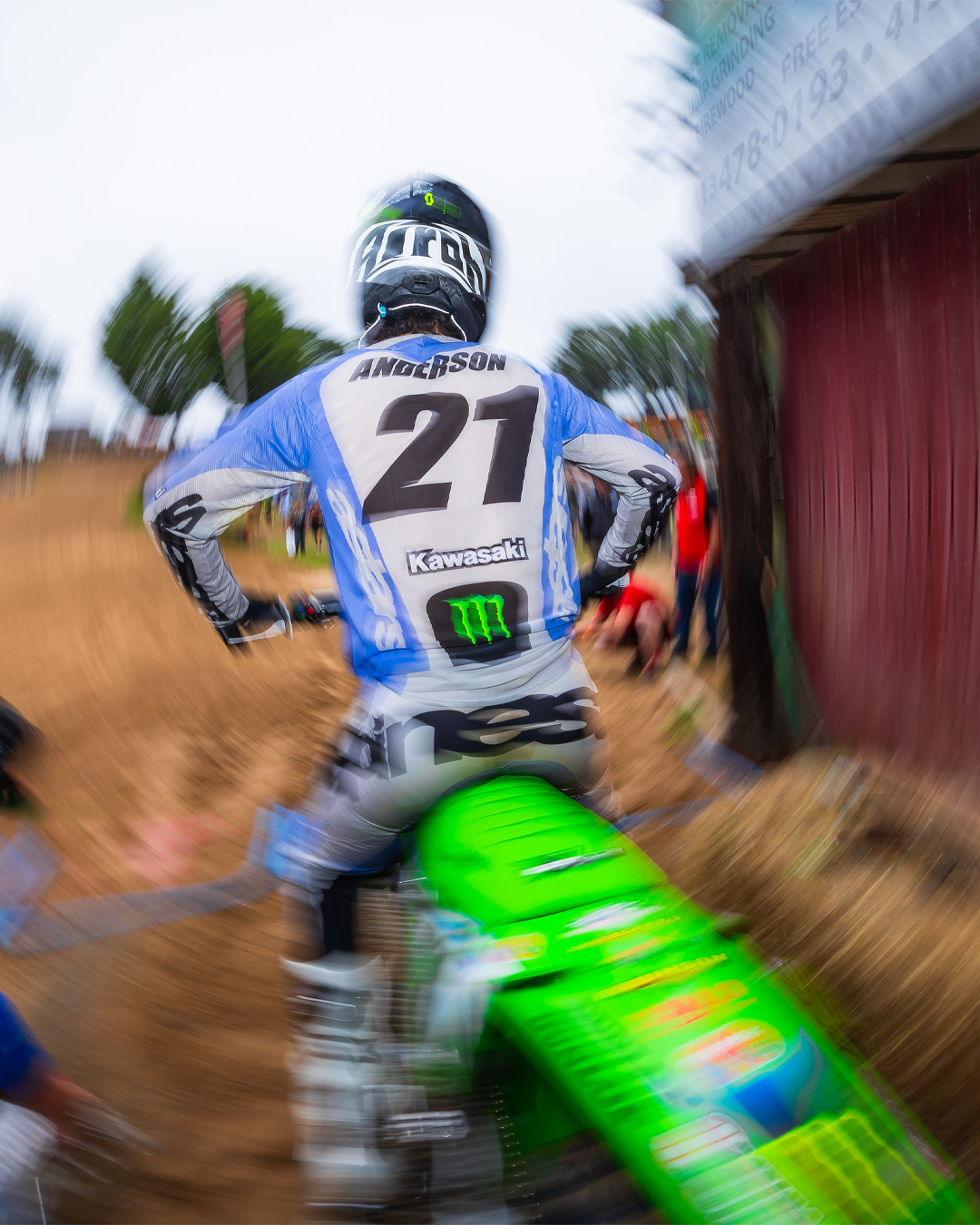 Jason Anderson wearing an Alpinestars mx gear set before a race near a red barn with blurred motion effect