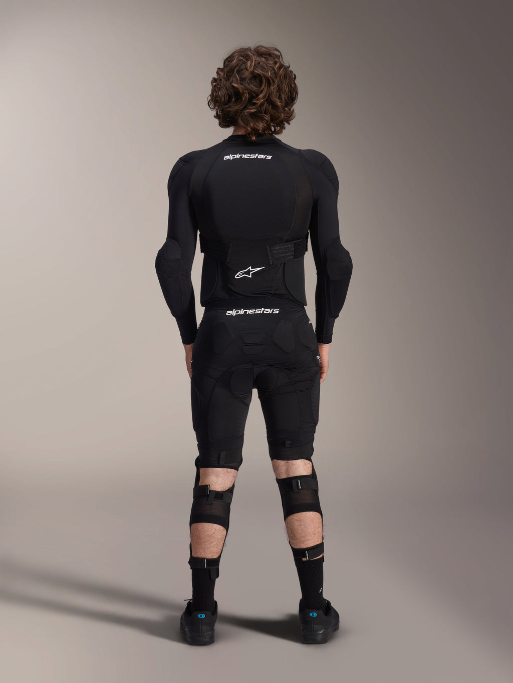 Casaco de Proteção Alpinestars A-Impact Plasma - Manga Comprida, vista traseira, preto com logótipos Alpinestars brancos, usado com calções de proteção e joelheiras para proteção de corpo inteiro em mountain bike