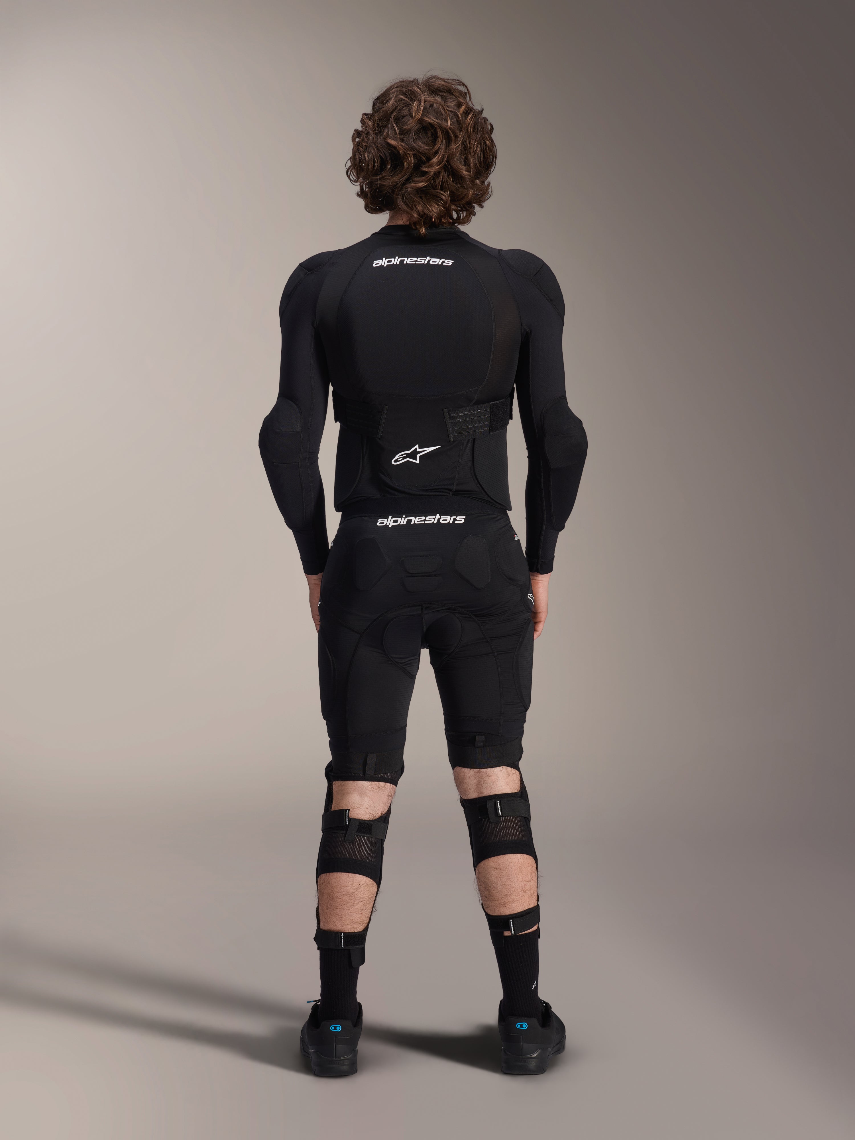 Casaco de Proteção Alpinestars A-Impact Plasma - Manga Comprida, vista traseira, preto com logótipos Alpinestars brancos, usado com calções de proteção e joelheiras para proteção de corpo inteiro em mountain bike