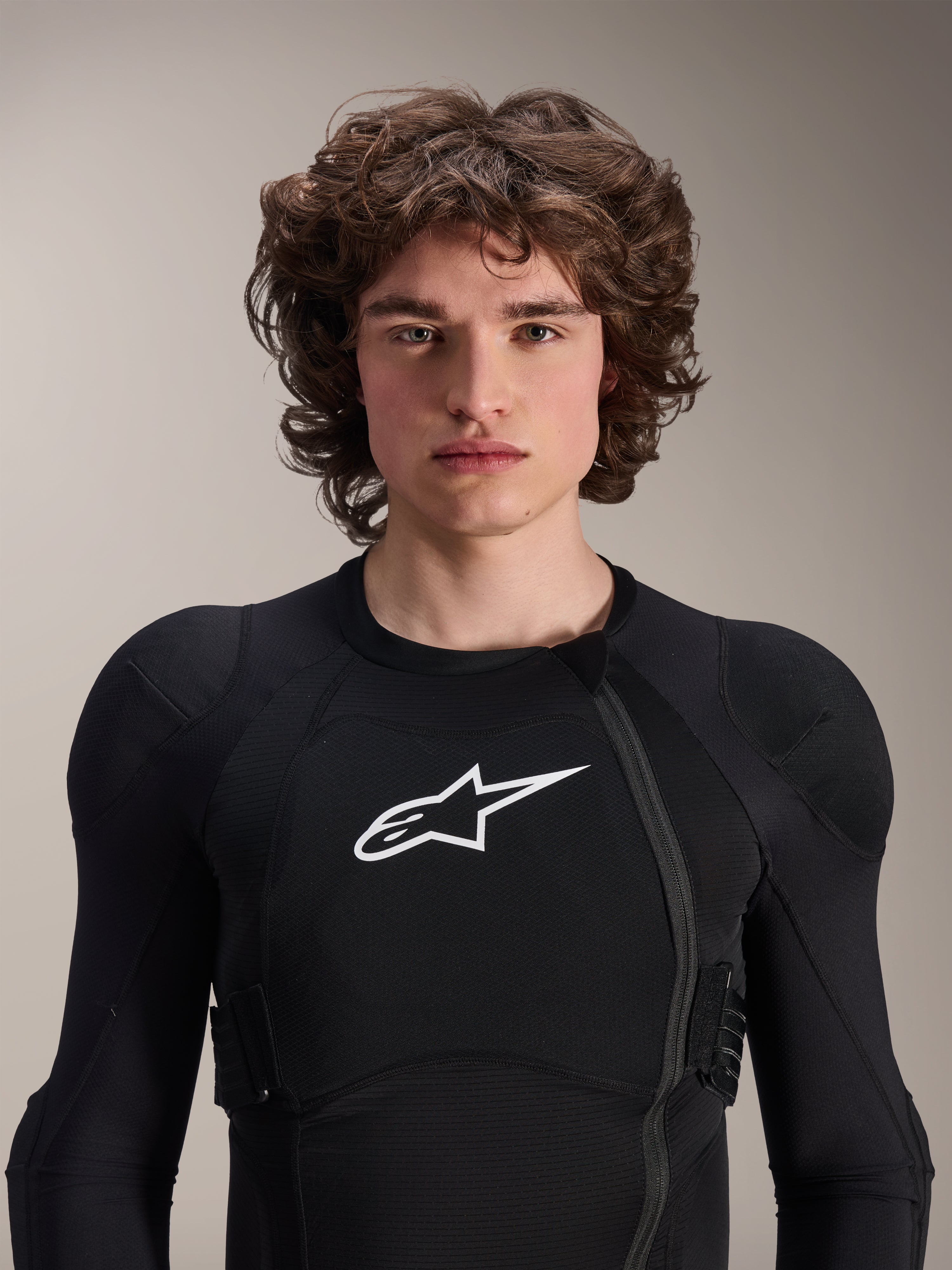 Modelo masculino a usar o Casaco de Proteção Alpinestars A-Impact Plasma - Manga Comprida, preto com logótipo Astars branco, com fecho de correr frontal deslocado e acolchoamento integrado, equipamento de proteção profissional para BTT