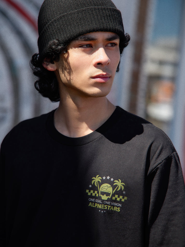 Alpinestars Order CSF Tee, t-shirt de manga curta, preta, logótipo verde lima com capacete e palmeiras e texto One Goal One Vision, modelo a usar um gorro preto, streetwear casual inspirado no desporto motorizado