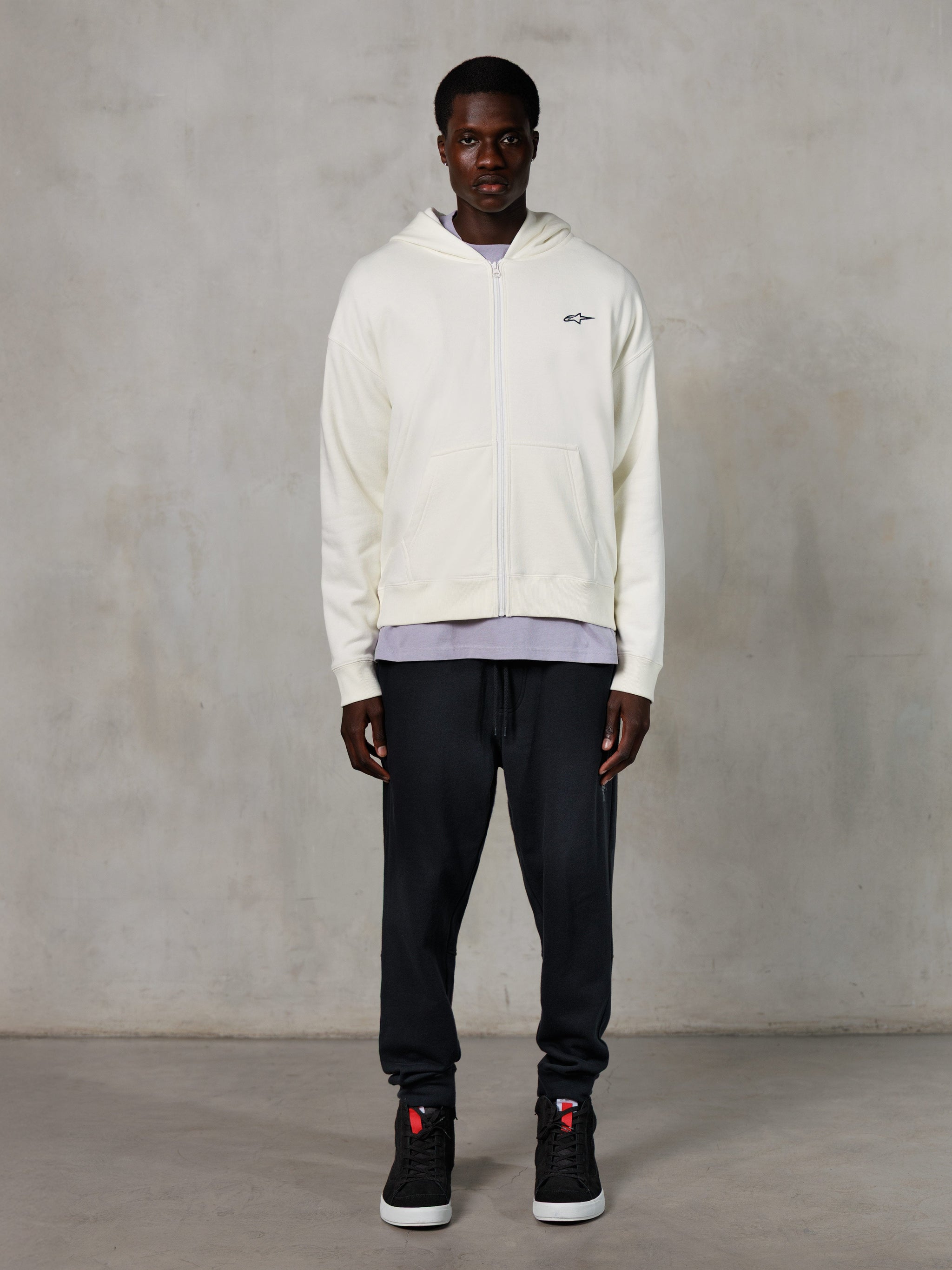 Alpinestars Essentials Ageless Zip Hoodie, streetwear casual, off-white com logótipo preto subtil no peito, fecho de correr frontal integral, design com capuz, corte relaxado, combinado com calças de fato de treino pretas e sapatilhas