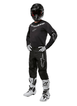 Conjunto de Equipamento Alpinestars 2024 Fluid Graphite, equipamento completo de corrida de motocross, preto com logótipos cinzentos e brancos, com camisola e calças usadas com capacete preto a condizer, luvas e botas brancas e pretas, concebido para proteção em todo-o-terreno