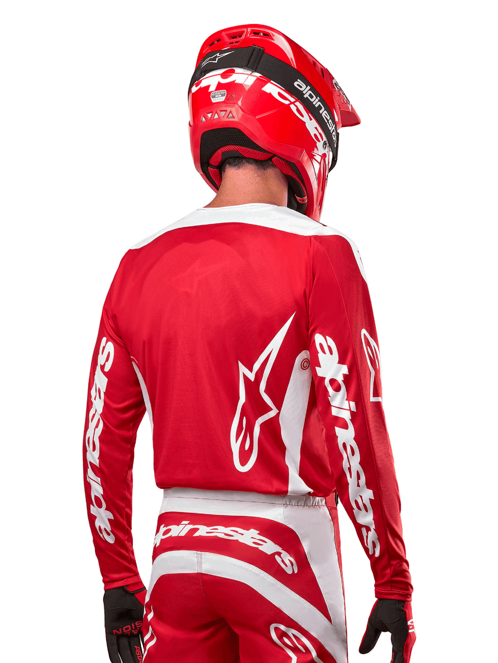 Piloto de motocross com camisola Alpinestars 2024 Fluid Lurv, em vermelho Mars e branco, vista traseira com logótipo Alpinestars branco nas costas e branding nas mangas, acompanhado por capacete vermelho e luvas pretas, equipamento profissional de corrida todo-o-terreno