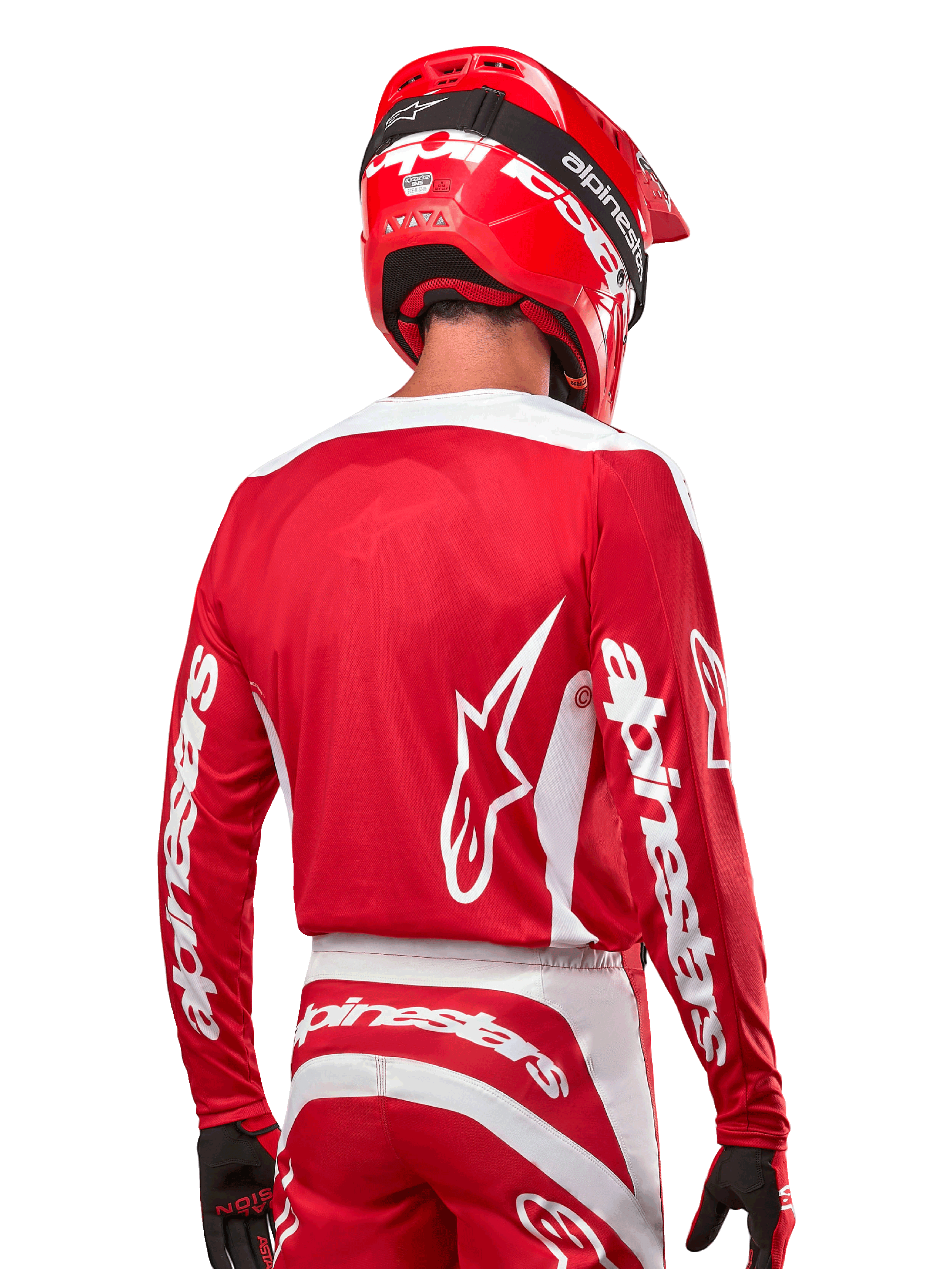 Piloto de motocross com camisola Alpinestars 2024 Fluid Lurv, em vermelho Mars e branco, vista traseira com logótipo Alpinestars branco nas costas e branding nas mangas, acompanhado por capacete vermelho e luvas pretas, equipamento profissional de corrida todo-o-terreno