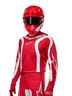 Alpinestars 2024 Fluid Lurv Jersey, camisola de motocross, vermelho Mars e branco, usada com capacete e luvas vermelhas a condizer, design desportivo arrojado com riscas curvas brancas e logótipos Alpinestars