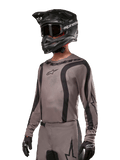 Alpinestars 2024 Fluid Lurv Jersey, Motocross Jersey, Mud Black and Gray, long-sleeve design with curved black stripes and logos, worn with matching pants and a black motocross helmet, coordinated off-road racing setup