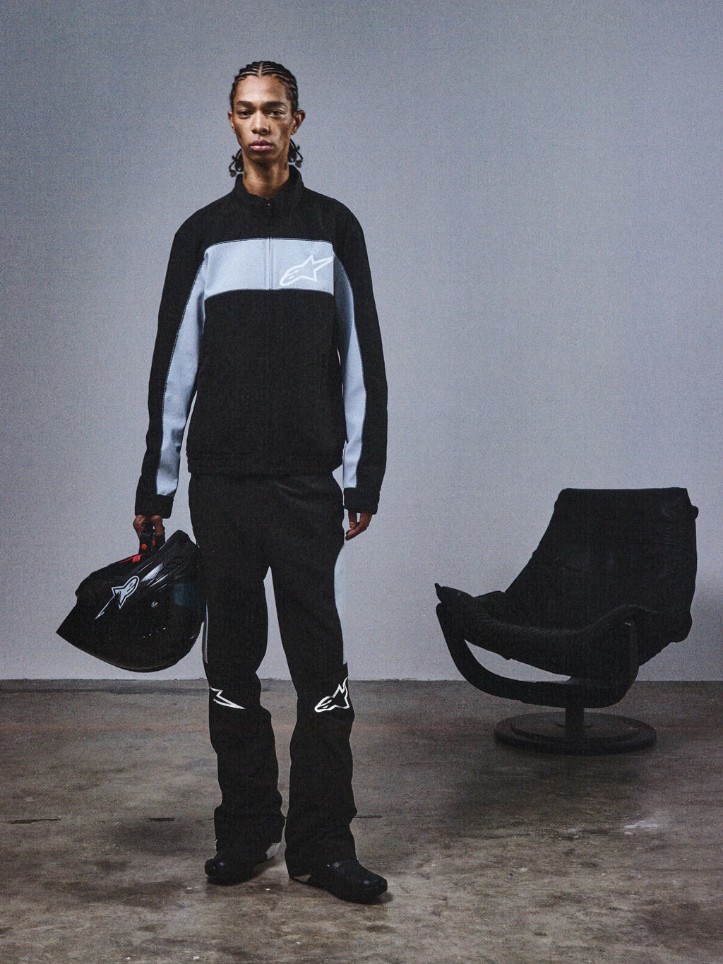 Alpinestars RSRV Track Jacket, casaco desportivo preto e cinzento com logótipo de estrela, pessoa com capacete a condizer, estilo urbano minimalista, coleção streetwear premium