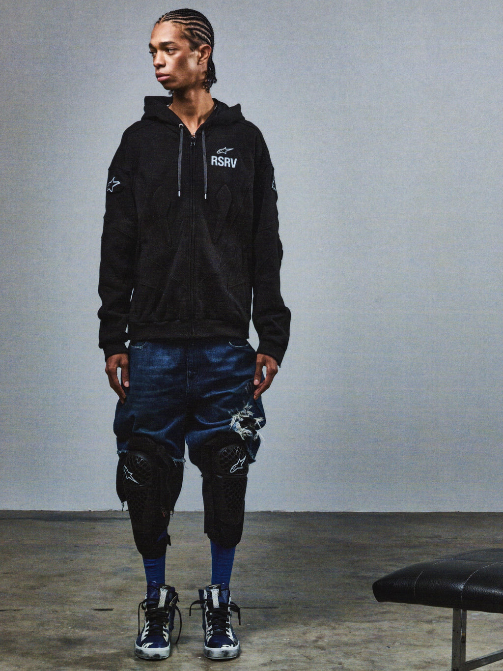 Alpinestars RSRV GP Hoodie, sweatshirt preta unissexo com logótipo RSRV, usada com calções de ganga desgastados azuis e joelheiras pretas, estilo urbano streetwear