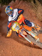 Enduro rider in action on an orange dirt bike, wearing the Alpinestars Pro-Dura Jersey in Navy, Hot Orange, and White, featuring a lightweight and breathable design with bold branding for off-road performance.
