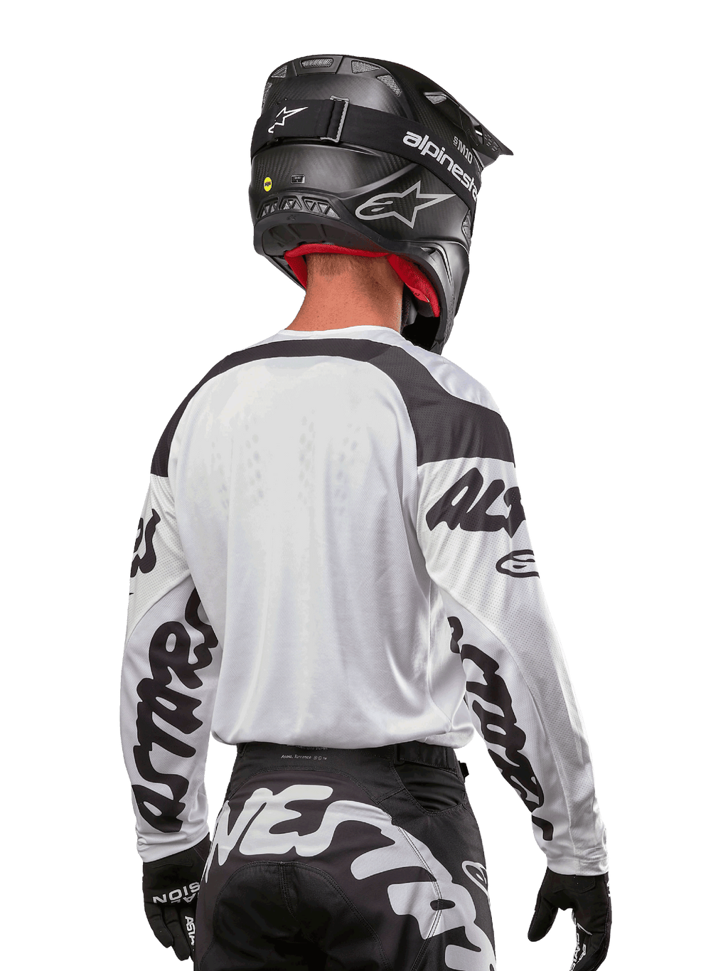 Camisola Alpinestars 2024 Racer Hana, branca e preta, vista traseira mostrando o ajuste ergonómico e logótipos de destaque nas mangas, combinada com um capacete de motocross preto e calças pretas e brancas a condizer, equipamento de alta performance para condução off-road