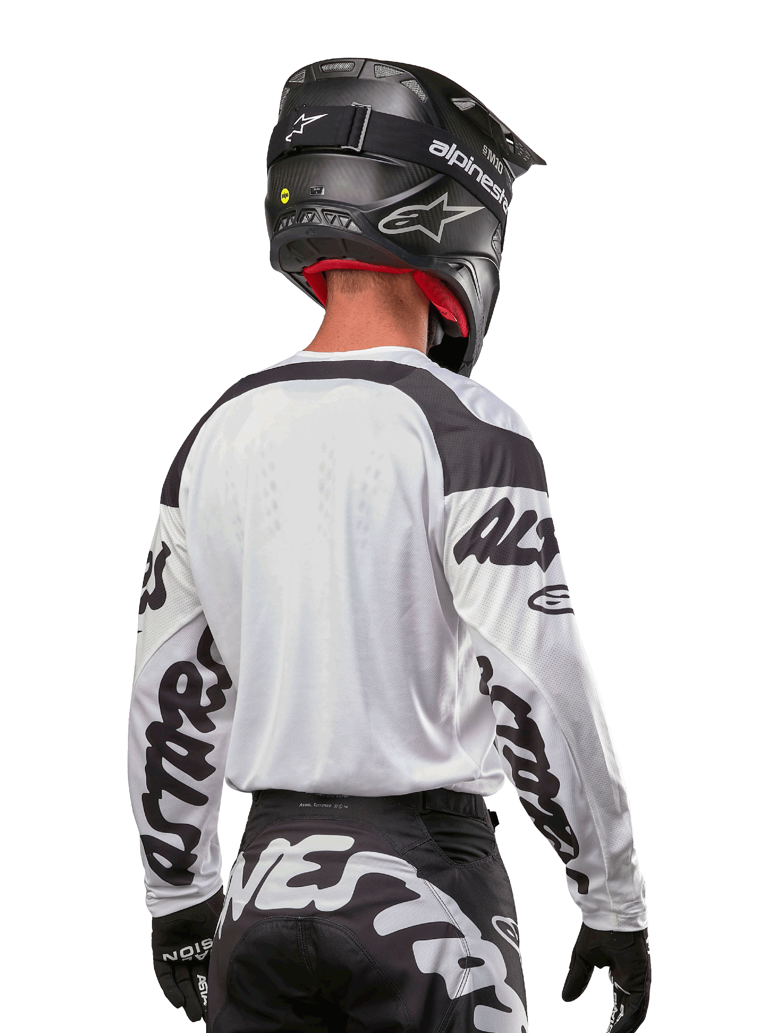 Camisola Alpinestars 2024 Racer Hana, branca e preta, vista traseira mostrando o ajuste ergonómico e logótipos de destaque nas mangas, combinada com um capacete de motocross preto e calças pretas e brancas a condizer, equipamento de alta performance para condução off-road