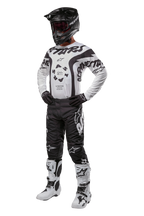 Equipamento de motocross Alpinestars Racer Hana 2024, incluindo calças pretas com logótipos brancos, camisola branca e preta com padrões gráficos, capacete preto, óculos de proteção, luvas pretas e botas de motocross brancas e pretas.