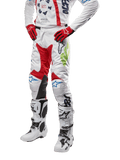 2024 Racer Hana Pants, Motocross Racing Pants, White with Red Blue and Lime Green accents, featuring protective design with leather knee panels, worn with matching jersey, red gloves, and white boots with buckles, sporty motorsports outfit