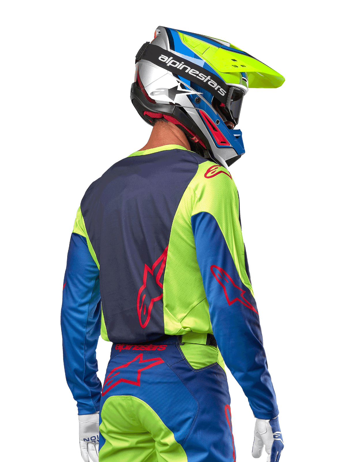 Piloto de motocross a usar a camisola Alpinestars 2024 Racer Hoen em Yellow Fluo e Blue Night Navy, com um logótipo de estrela vermelha nas costas, calças de motocross a condizer e um capacete de corrida coordenado, vista traseira evidenciando o design ergonómico para performance em todo-o-terreno.