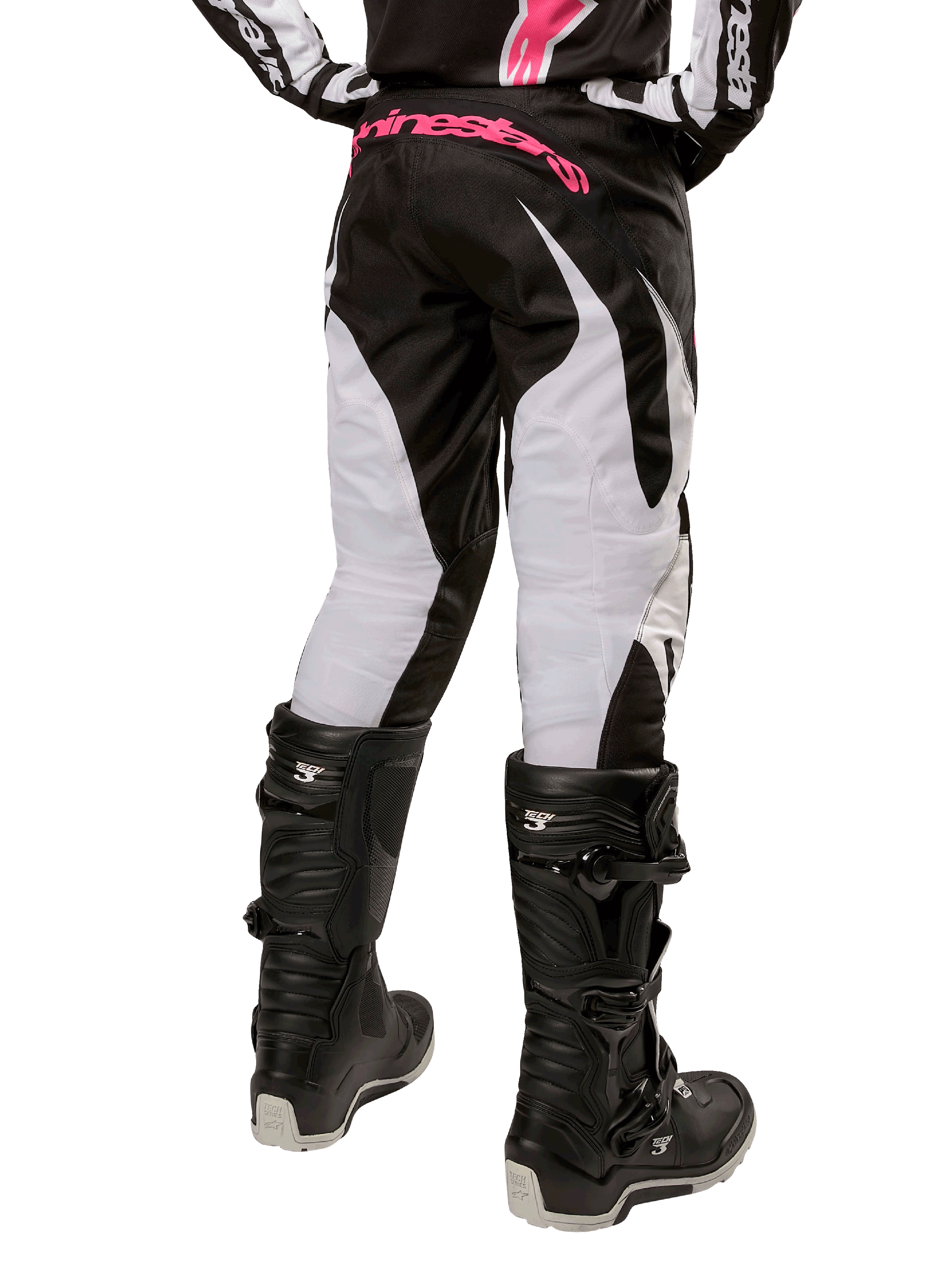Alpinestars Stella Fluid Pants 2024 para Mulher, calças de motocross, pretas e brancas, vista traseira com painéis brancos nas pernas e logótipo cor-de-rosa no cós, usadas com botas Tech 3 pretas, equipamento durável para todo-o-terreno