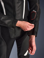 Pormenor do Fato de Cabedal Alpinestars Stella GP-R7 de 2 Peças em preto, com foco no ajuste do fecho de correr no antebraço, apresentando construção em pele perfurada, detalhes em branco e a marca de compatibilidade Tech-Air na manga.