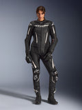 Mulher a usar o Fato de Cabedal Alpinestars Stella GP-R7 de 2 Peças em preto com detalhes brancos, com painéis de pele perfurada e logótipos brancos no peito e nos joelhos, combinado com luvas e botas de corrida pretas a condizer, equipamento profissional de motociclismo