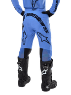 Alpinestars 2024 Supertech Dade Pants, calças de motocross, azul claro, vista traseira com grandes logótipos pretos no assento e nas pernas, combinadas com botas Alpinestars Tech 10 pretas, corte atlético para performance profissional em todo-o-terreno