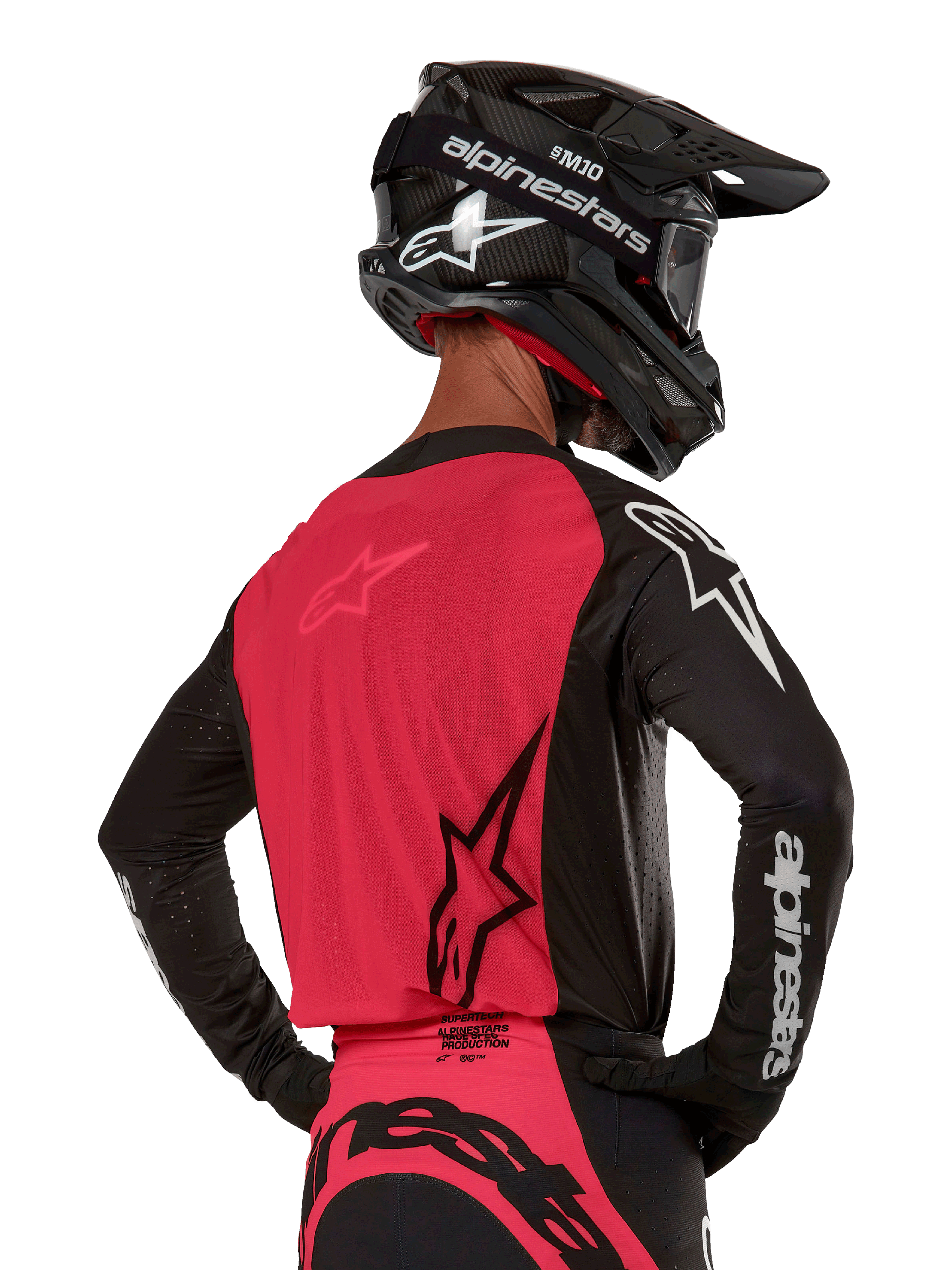 Alpinestars 2024 Supertech Ward Jersey, camisola de motocross, preto e vermelho berry, vista traseira com painel de malha vermelho e mangas pretas com logótipos brancos, usada com capacete de fibra de carbono preto e luvas, ajuste de corrida atlético para condução todo-o-terreno