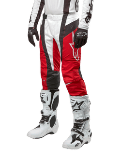 Alpinestars 2024 Techstar Ocuri Pants, calças de motocross, vermelho Mars, branco e preto, usadas com camisola branca e preta a condizer, luvas pretas e botas de corrida brancas com fivelas, equipamento de proteção técnico apresentado sobre um fundo branco