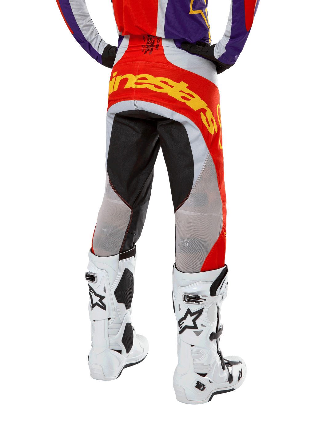 Alpinestars 2024 Techstar Ocuri Pants, calças de motocross, laranja, roxo e preto, vista traseira da cintura para baixo, logótipo amarelo em destaque no assento, painéis técnicos pretos e cinzentos, combinadas com botas de motocross brancas