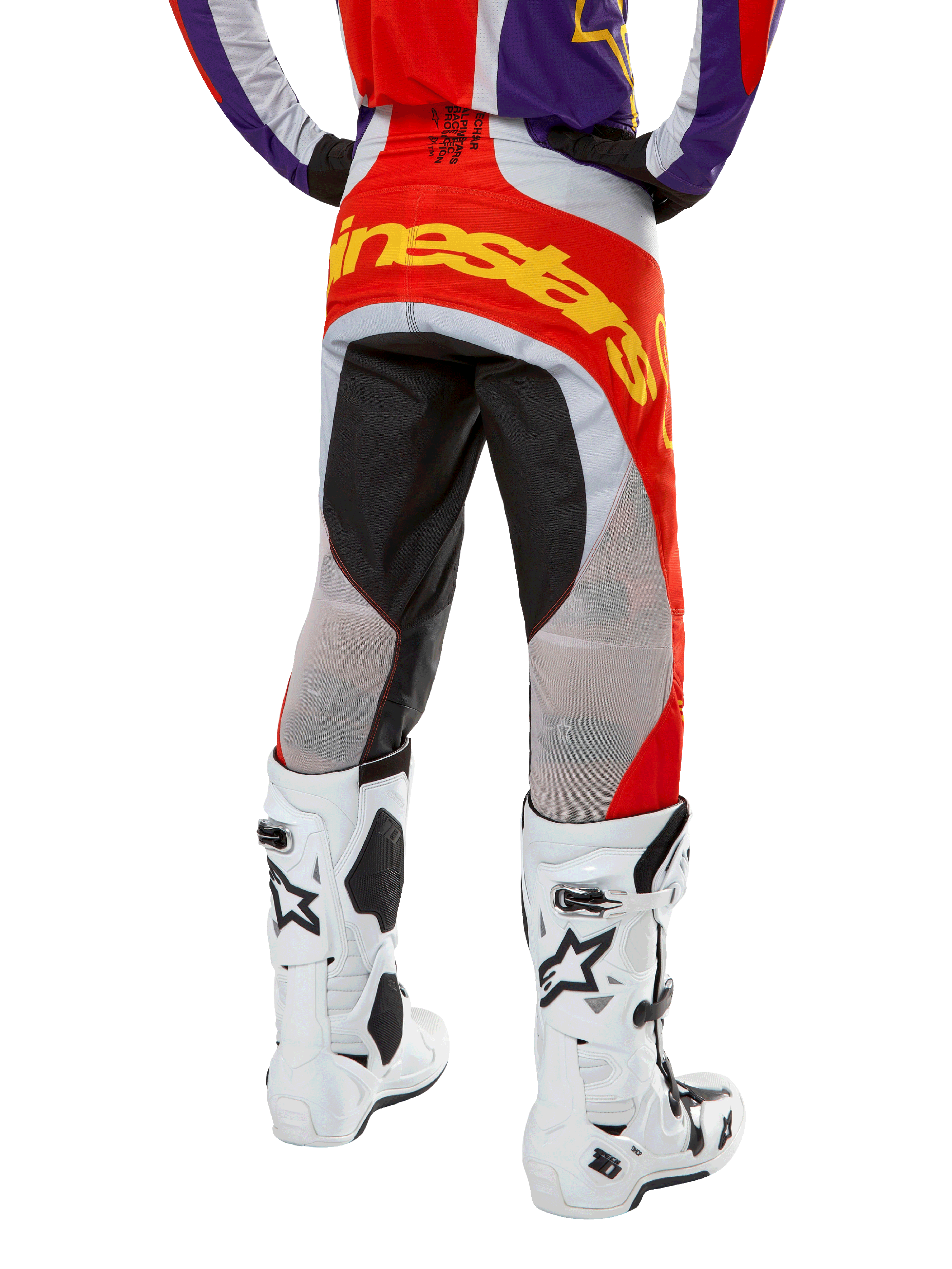 Alpinestars 2024 Techstar Ocuri Pants, calças de motocross, laranja, roxo e preto, vista traseira da cintura para baixo, logótipo amarelo em destaque no assento, painéis técnicos pretos e cinzentos, combinadas com botas de motocross brancas