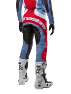 Alpinestars 2024 Techstar Ocuri Pants, calças de motocross em azul claro, vermelho Mars e branco, vista traseira destacando o grande logótipo Alpinestars vermelho no assento, combinadas com botas de corrida brancas e camisola a condizer