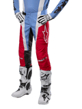 Alpinestars 2024 Techstar Ocuri Pants, calças de motocross, azul claro, vermelho Mars e branco, usadas com camisola azul claro e botas brancas, com o logótipo de estrela na coxa e joelhos reforçados, equipamento completo de corrida todo-o-terreno
