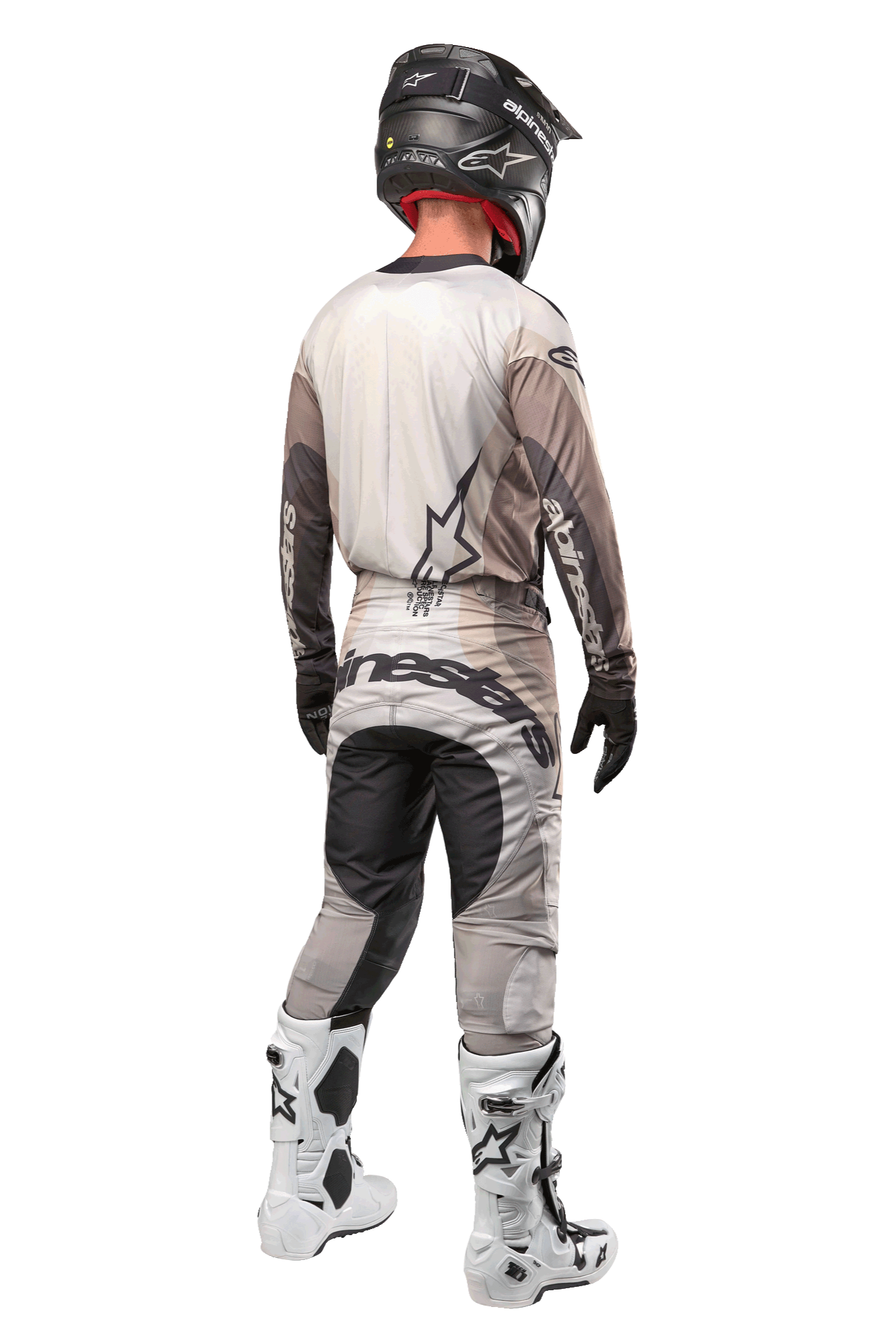 Alpinestars 2024 Techstar Pneuma Pants, calças de motocross, Areia Escura e Cinzento Iron Dust, vista traseira usada por um piloto com uma camisola a condizer, botas brancas e pretas e um capacete preto, com logótipo Alpinestars proeminente no assento e painéis escuros reforçados