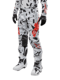 Alpinestars 2024 Techstar Rantera Pants, calças de motocross, camuflado cinza com padrão abstrato preto e vermelho, usadas com camisola a condizer, luvas pretas e botas de motocross brancas, concebidas para corridas de alta performance em todo-o-terreno