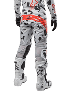 Alpinestars 2024 Techstar Rantera Pants, calças de motocross, camuflado cinzento Haze com padrões pretos e um logótipo Alpinestars grande em vermelho no assento, vista traseira com botas brancas e equipamento de corrida a condizer