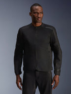 Modelo masculino a usar Casaco Alpinestars C-1 Air em Preto, casaco de motociclismo contemporâneo com amplos painéis de malha técnica e fecho de correr frontal integral, combinado com calças de condução pretas a condizer, estética urbana e de deslocações diárias
