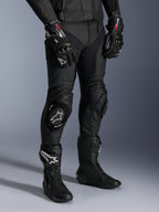 Missile V3 Leather Pants, Black Motorcycle Racing Pants, worn with matching GP Pro gloves and technical racing boots, premium leather construction with white logo knee sliders, professional racing aesthetic for track and road use