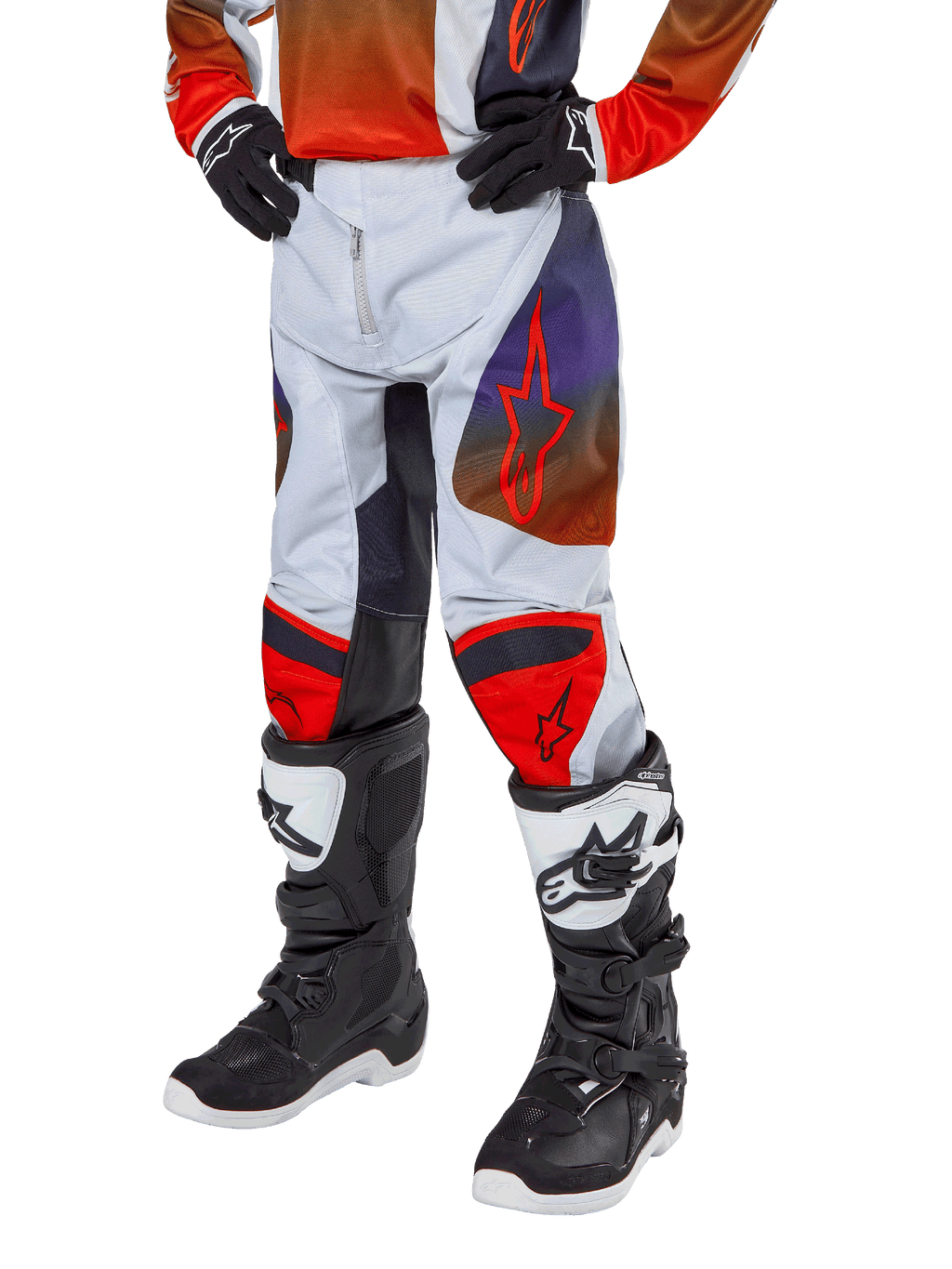 Alpinestars 2024 Youth Racer Hoen Pants, calças de motocross para jovens, cinzento claro com detalhes em laranja vibrante e preto, com logótipos de estrela vermelha nas coxas e painéis vermelhos nos joelhos, usadas com botas pretas e brancas, design durável para todo-o-terreno