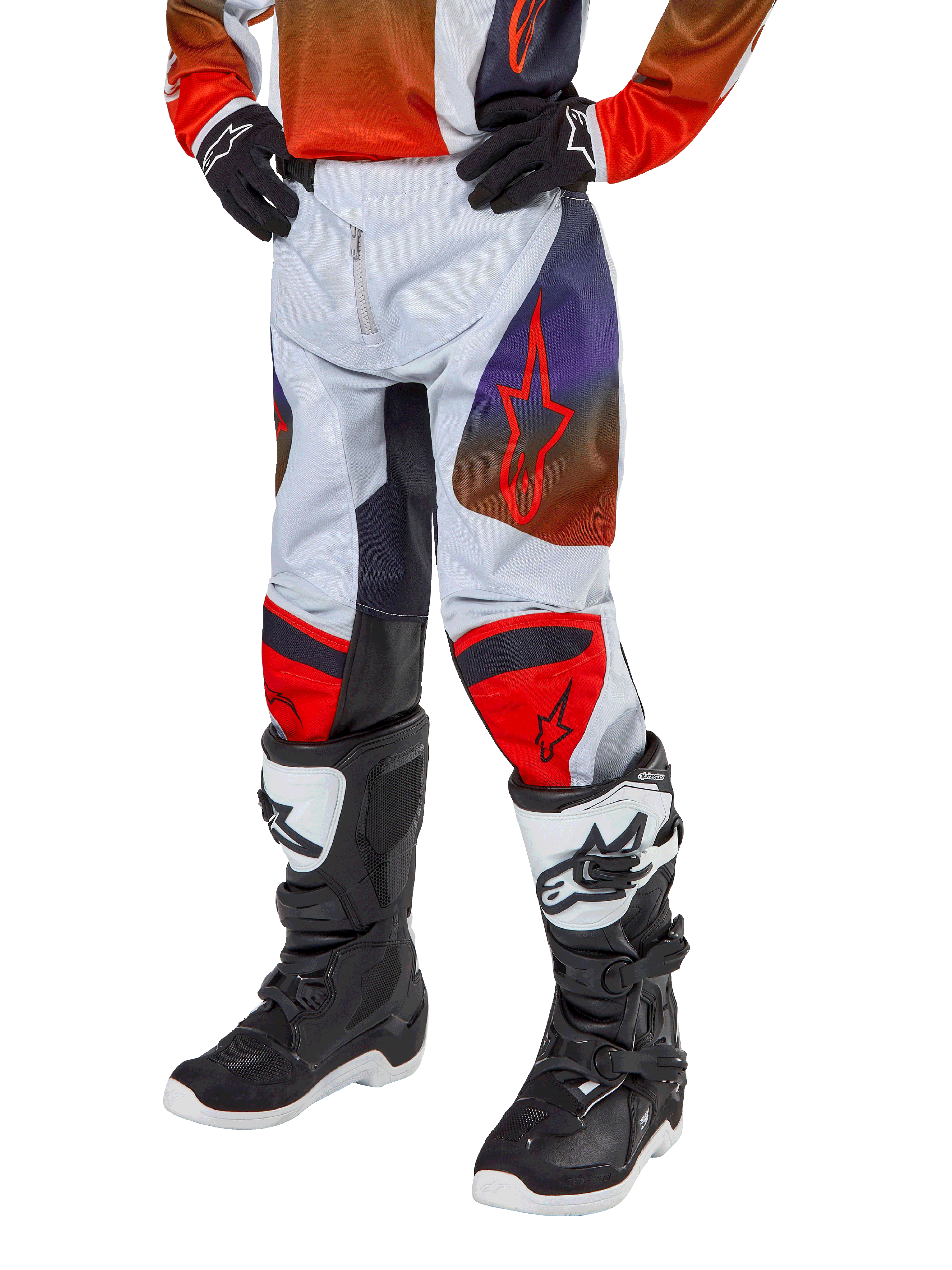 Alpinestars 2024 Youth Racer Hoen Pants, calças de motocross para jovens, cinzento claro com detalhes em laranja vibrante e preto, com logótipos de estrela vermelha nas coxas e painéis vermelhos nos joelhos, usadas com botas pretas e brancas, design durável para todo-o-terreno