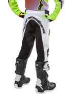 Alpinestars Youth 2024 Racer Lucent Pants, calças de motocross para jovens, brancas e pretas com detalhes néon, vista traseira mostrando o grande painel elástico traseiro e o logótipo Alpinestars, usadas com botas Alpinestars Tech Series pretas e brancas.