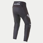 Alpinestars 2021 Techstar Phantom Pants, calças de motocross, pretas e brancas, vista traseira com logótipo ASTARS branco na cintura e na coxa lateral, painéis de malha texturizada cinzento carvão nas pernas, e design de ajuste de performance para competição